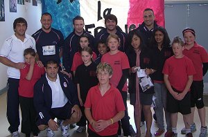 North Ainslie Primary join members of the French Rugby League team in front of the French banner made by the students