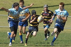 Patrick Brandon runs the ball but is dwarfed by the bigger St Joseph’s Aberdeen forwards during their Under-13s Country Cup Final played at Apex Oval yesterday